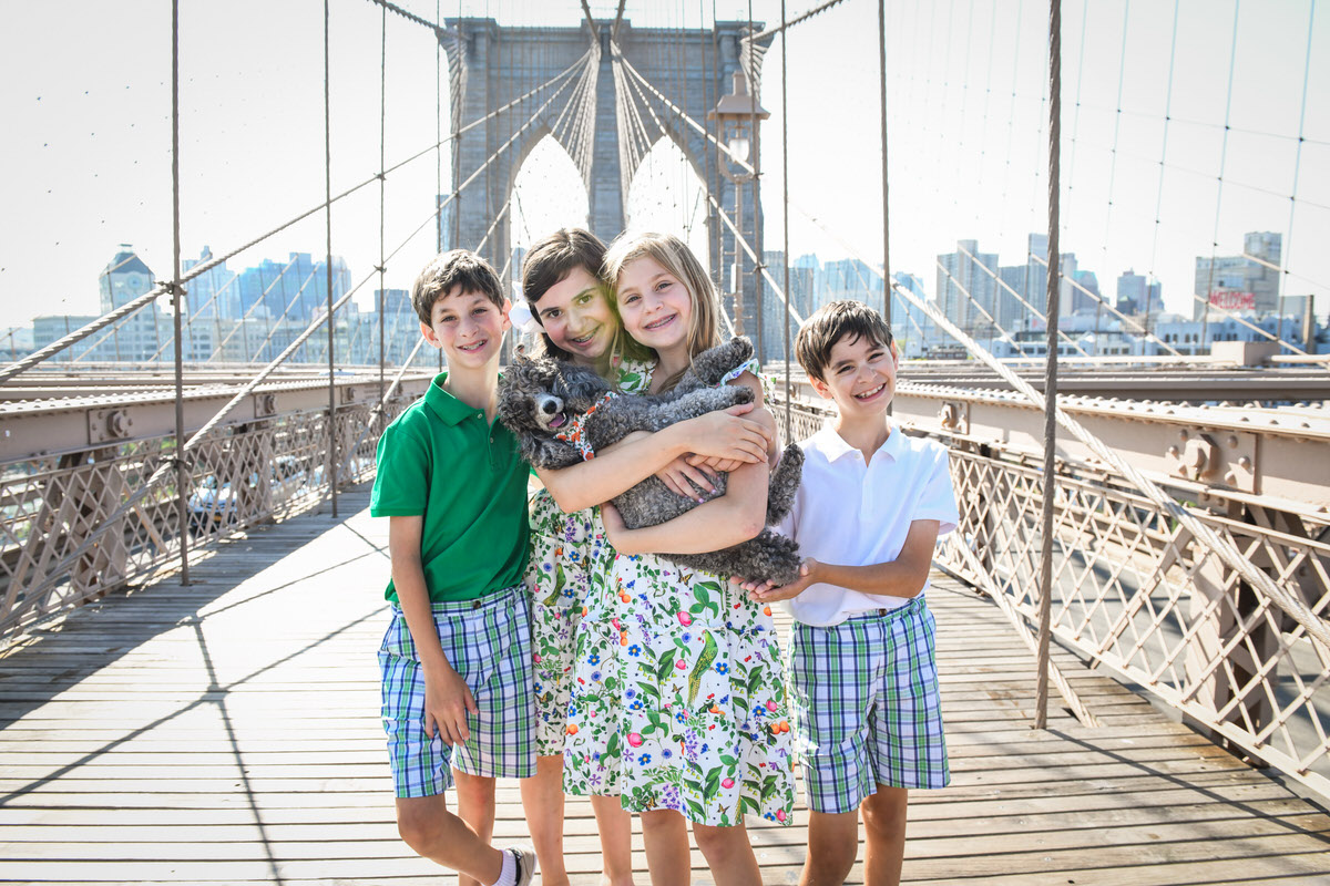 An example of where to take family photos showing four kids holding a dog and standing on the Brooklyn Bridge