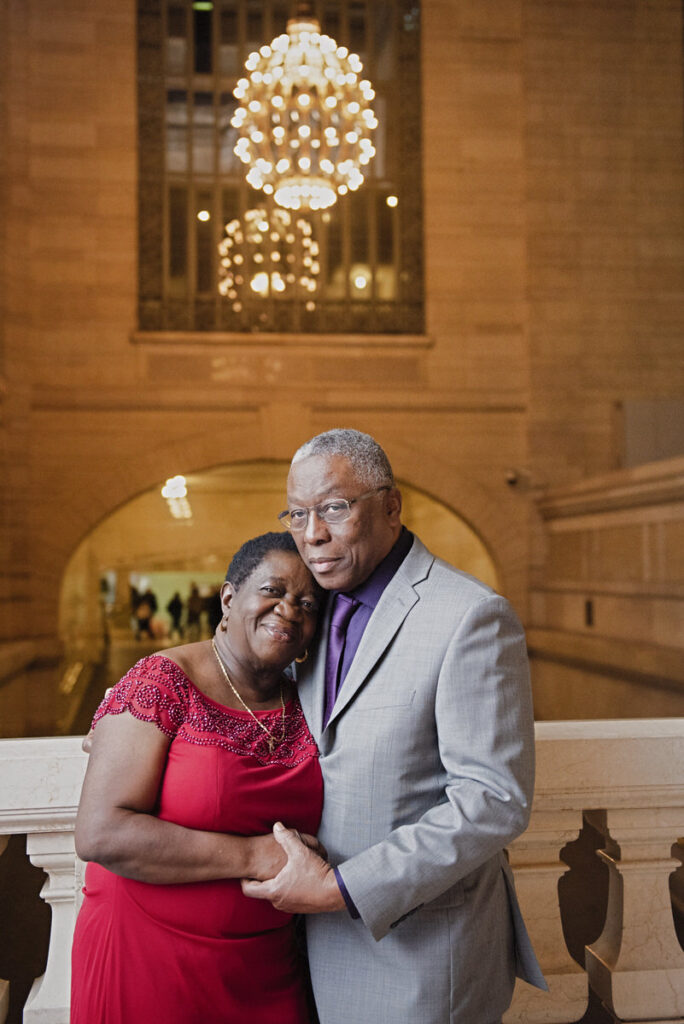 A couple holding each other softly and smiling in a train station 