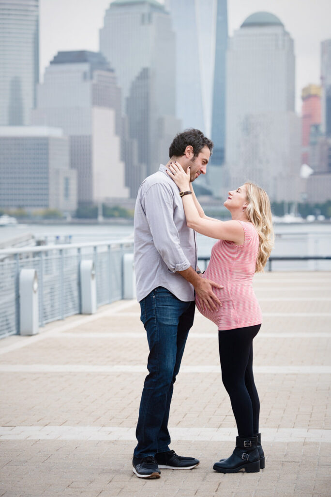 Two people, one reaching up towards the other's face and one holding the other's pregnant stomach 