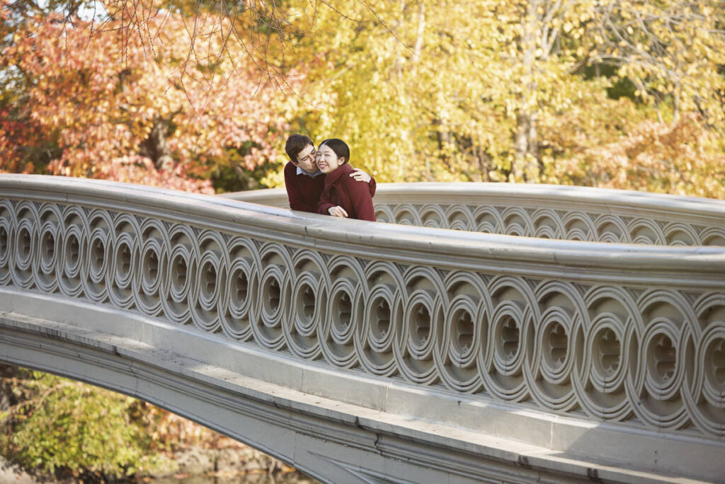 A person kissing their partner while they stand on a bridge 