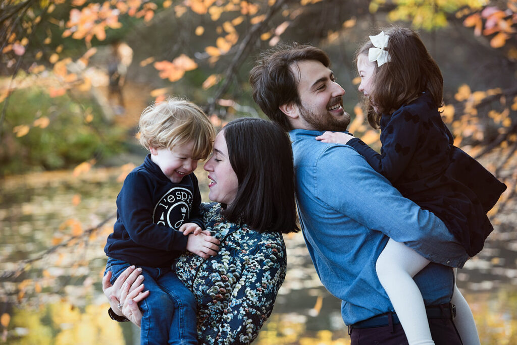 Two parents smiling as they each hold children 