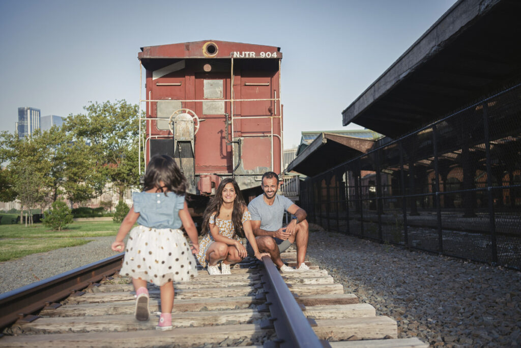 A child running on train tracks towards their parents 
