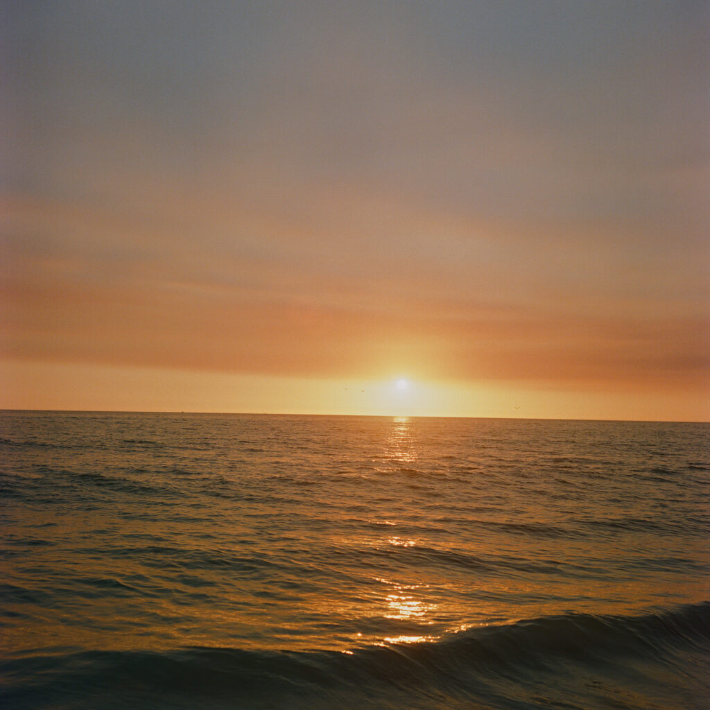 A serene sunset over the ocean, with the sun casting a golden reflection on the calm waves.