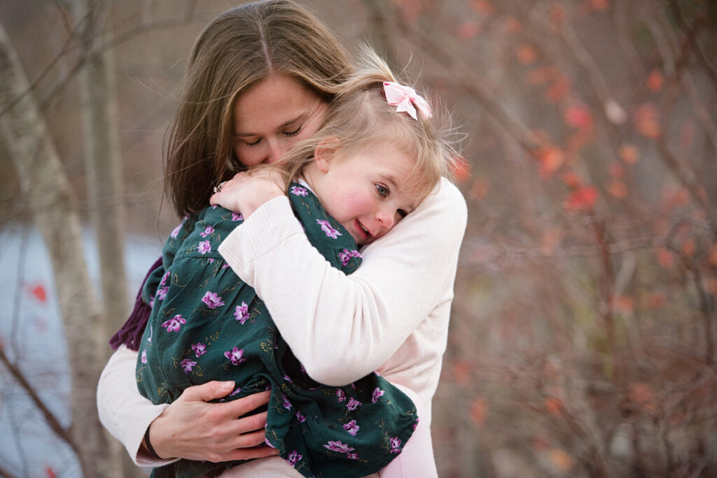 A mother tightly hugging a child 
