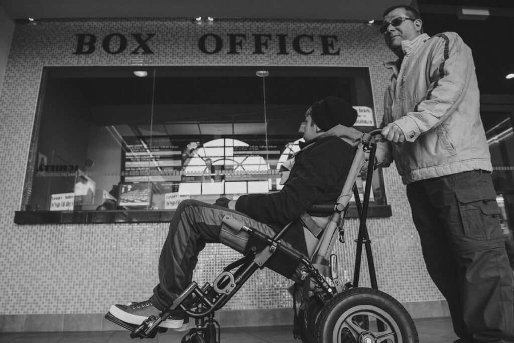 A parent pushing their child in a wheelchair 
