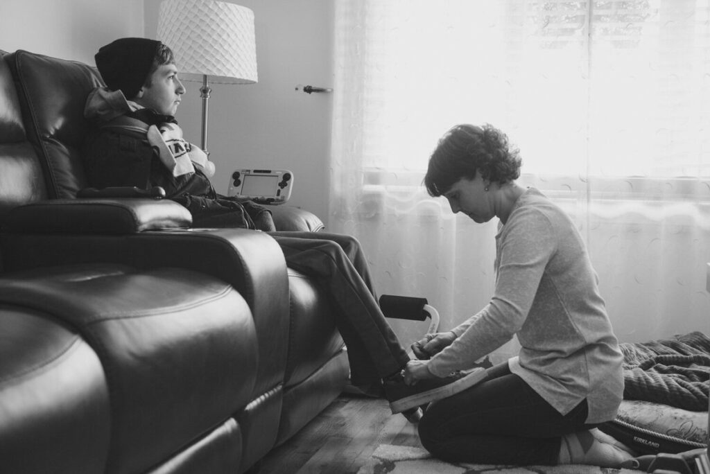 A mom helping a boy tie his shoes 
