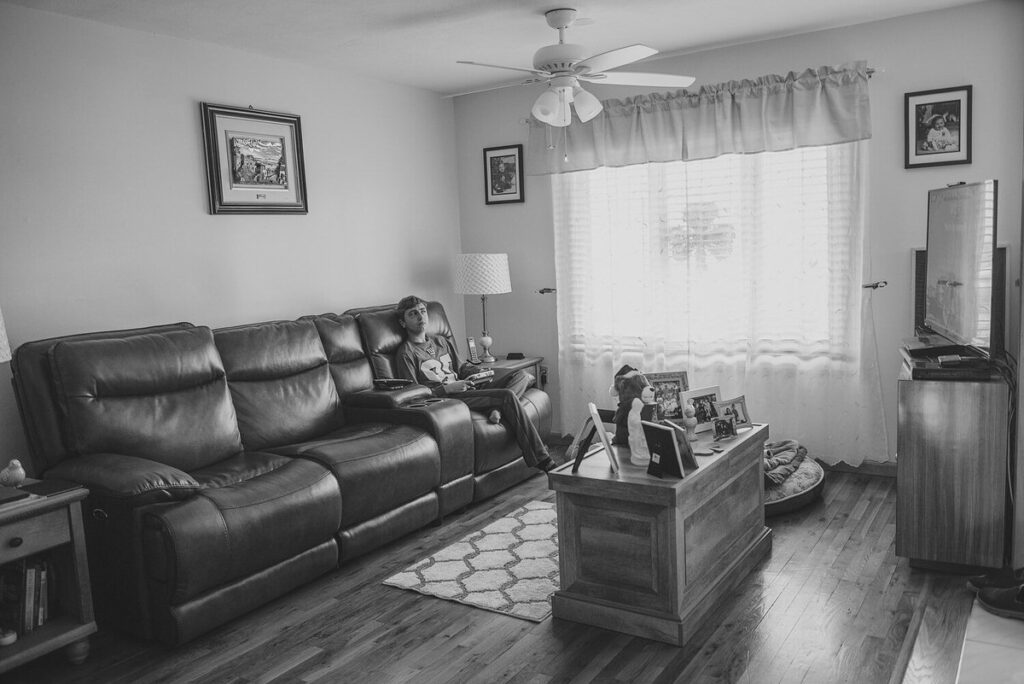 Black and white photo of a boy sitting on a couch 
