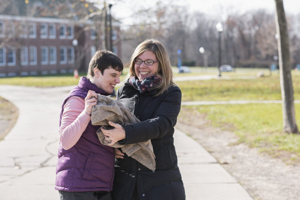 A mom hugging a child as they both smile 
