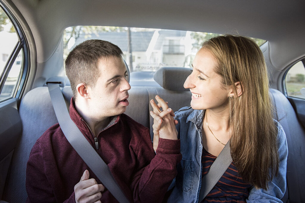 Two people in the back of a car holding hands 
