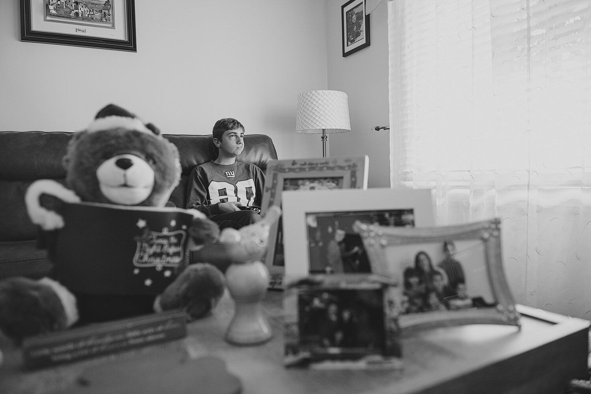 A boy sitting on a couch with a coffee table in from of him with pictures on it