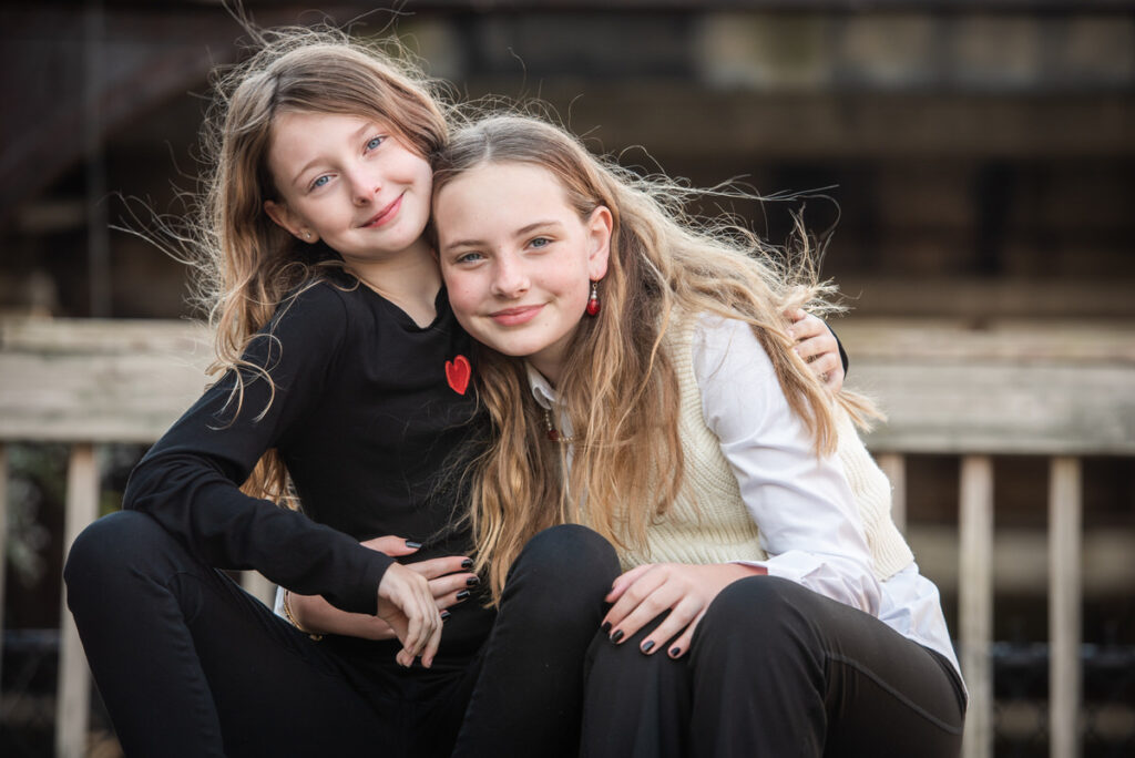 Two sisters with their arms around each other smiling 
