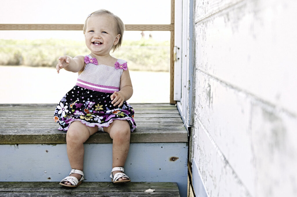 A baby smiling and sitting on a staircase 