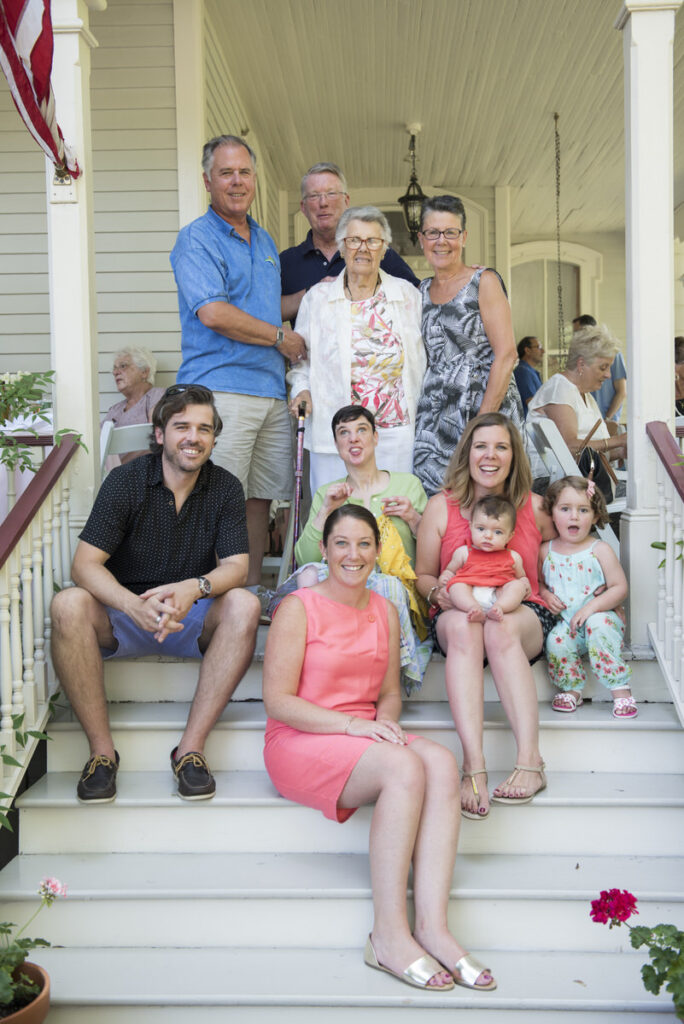 A large family sitting and standing on a staircase smiling 