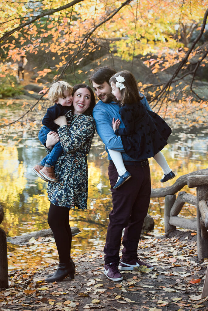 Two parents looking at each other smiling as they both hold kids 