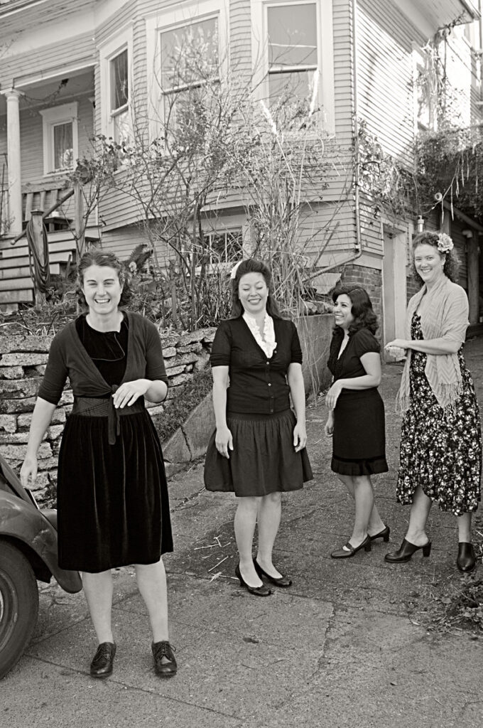 Black and white photo of a group of women standing in a driveway
