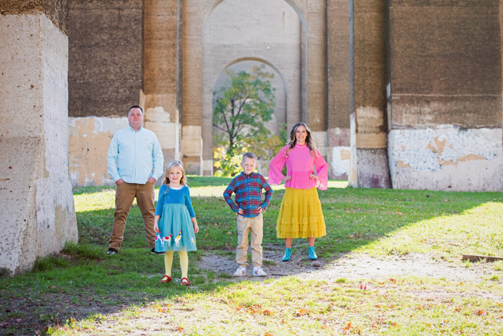 Two kids standing next to each other with their parents behind them 