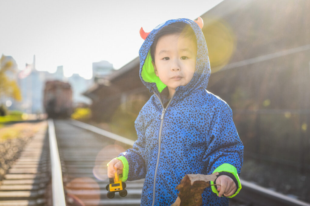 A small boy holding a toy truck in one hand and a leaf in the other